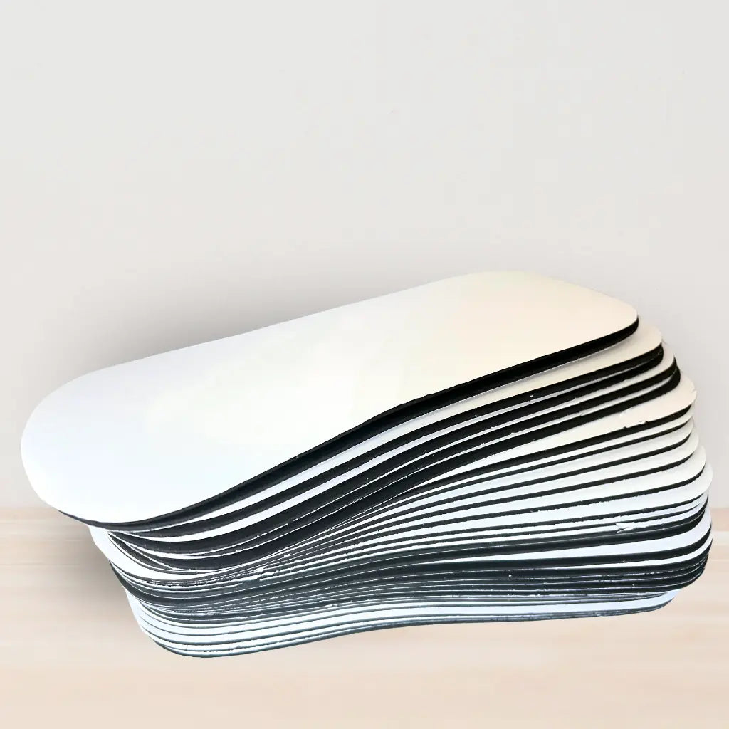 Stack of foam feet pads - white peelable layer on top with the black foam underneath. Neutral background.